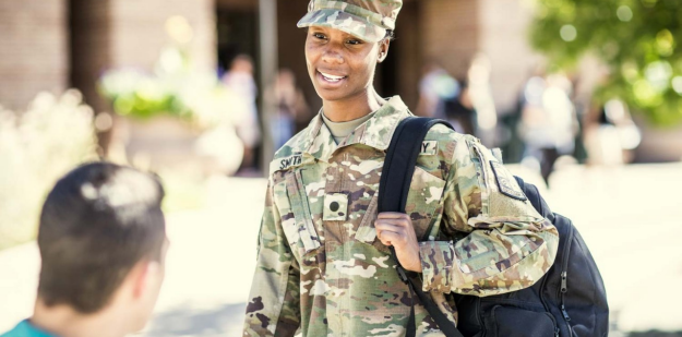 Cadet and civilian talking on a college campus. 